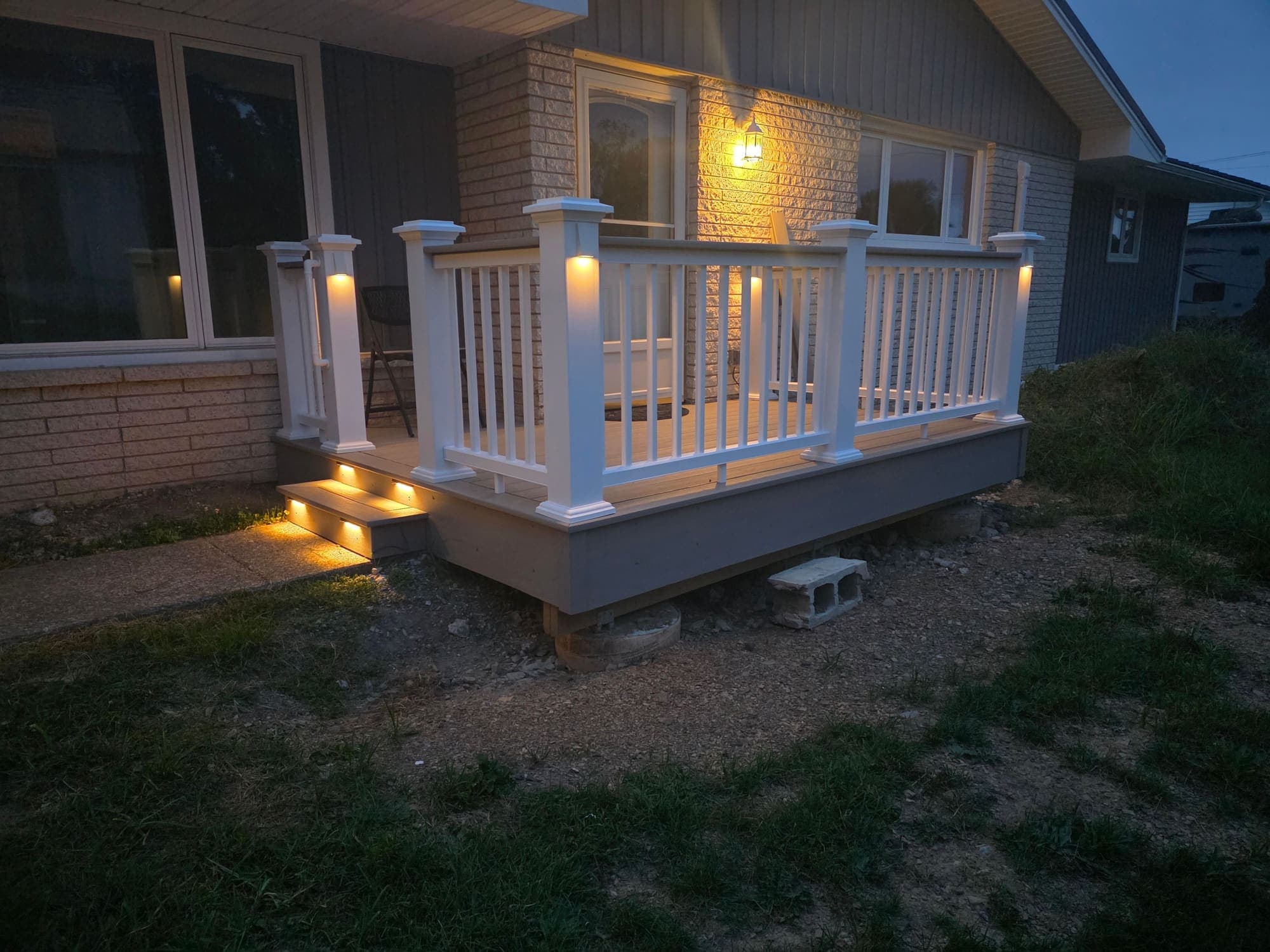 New porch with railings and step lighting, built by Odd Job Heroes, at dusk